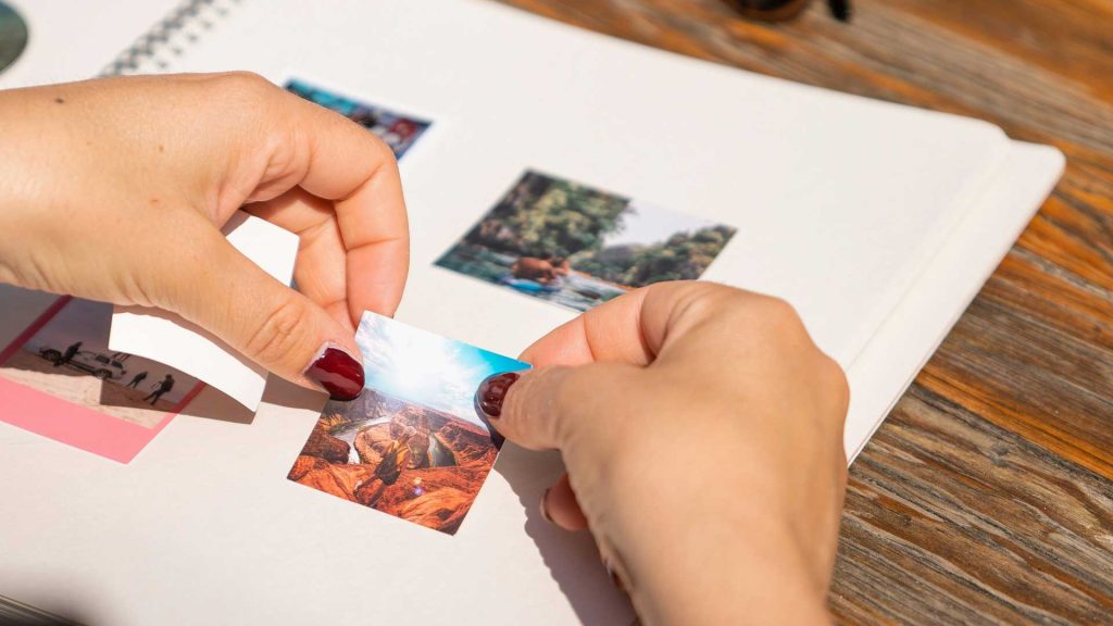 A person puts a photo in a scrapbook. 
