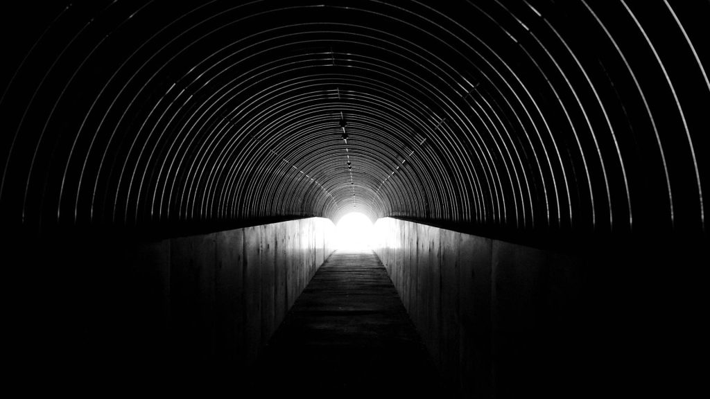 A long dark tunnel with a light at the end of it.